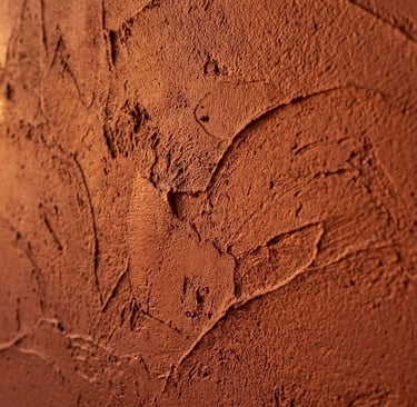 Textured reddish-brown clay plaster wall with visible trowel marks and earthy stucco finish.