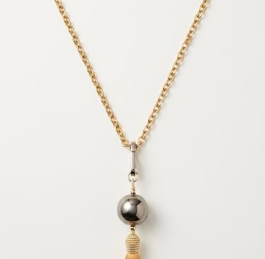 Elegant gold chain necklace featuring a grey metallic bead and a long yellow silk tassel pendant.