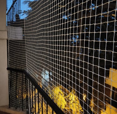 Side view of a balcony with pigeon netting installed, blending seamlessly with the building’s exteri