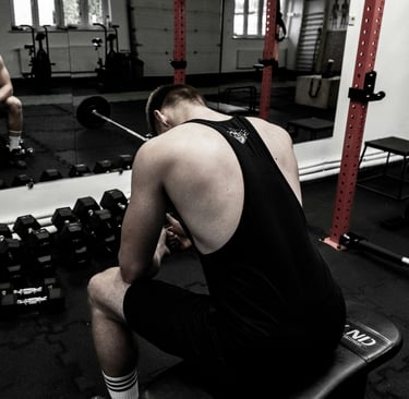Atleta de musculação descansando após treino intenso para evitar overtraining