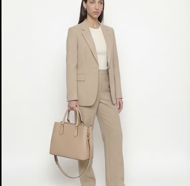 A woman in a beige tailored suit holding a matching leather tote bag for professional office wear.