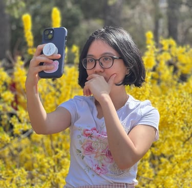 Annielou Bandong taking a photo of herself surrounded by yellow flowers on a bright sunny day.