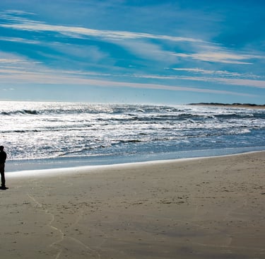 Photo of solitary man on beach looking out to sea