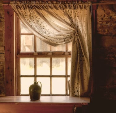 Photo of jug sitting on table in front of log cabin window