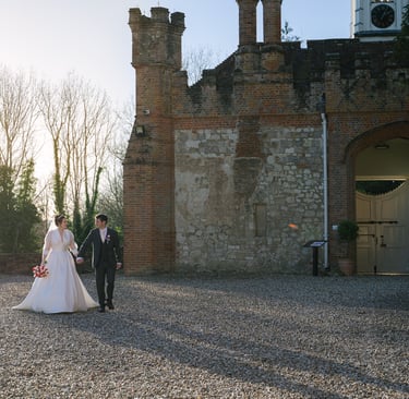 Couple walking through the courtyard at Farnham Castle during their wedding in Surrey