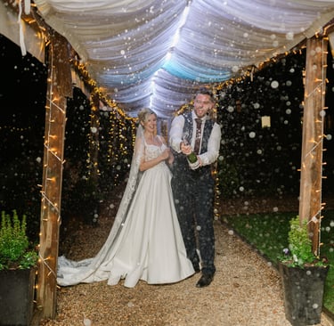 Couple spraying champagne under a pergola at The Mill House Hotel during their wedding