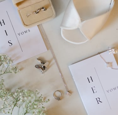 Wedding detail flat lay featuring rings, vow book, necklace, cufflinks and bridal shoes