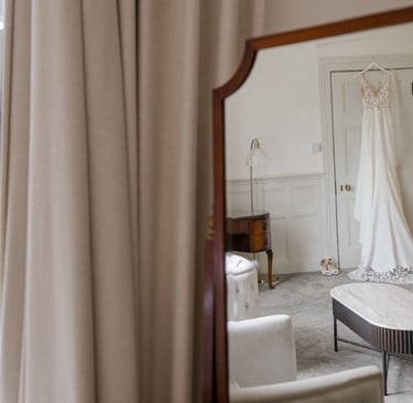 Mirror shot of wedding dress hanging from a door frame at Highley Manor
