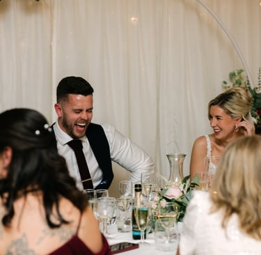 Couple laughing at the top table during their wedding reception at The Mill House Hotel