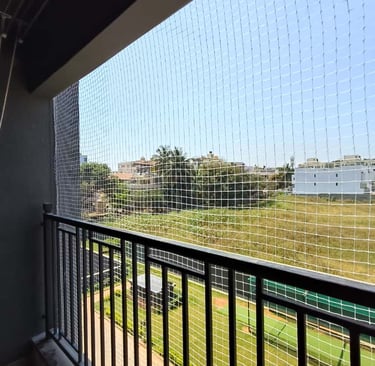 A cozy balcony enclosed with safety nets, plants thriving inside, showing a safe and green space.