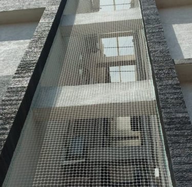 Installation team from Arjilli Safety Nets carefully fitting a safety net on a balcony railing.