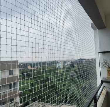 balcony secured with pigeon nets, city lights of Mumbai glowing softly in the background.