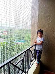 A child happily playing near a balcony secured with a sturdy safety net by Arjilli Safety Nets.