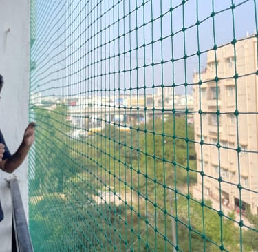 Happy family standing safely behind a newly installed balcony safety net in Anna Nagar.