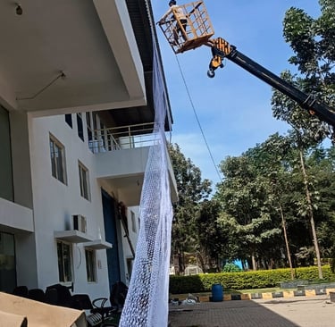 Team of Arjilli Safety Nets professionals working together to secure pigeon nets on a warehouse exte