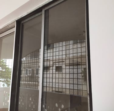 Installation process of a mosquito net on a window, showing the careful measurements and fitting.