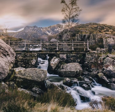 Rustic stone bridge over a mountain waterfall in Snowdonia National Park, Wales.