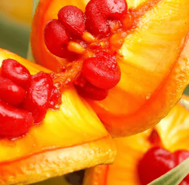 Macro shot of bright red seeds inside Pittosporum Angustifolium berries on a green leafy branch.
