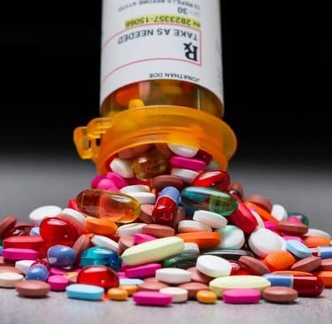 A variety of colorful prescription pills and capsules spilling from an orange medication bottle.