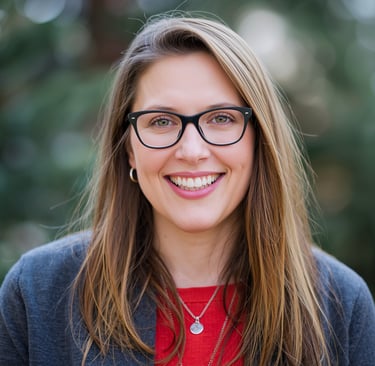 Smiling woman with long blonde hair and black glasses in a professional outdoor headshot.
