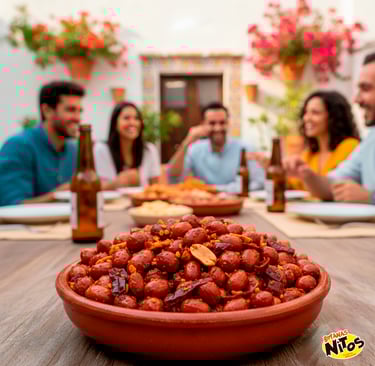 Spicy roasted peanuts in a clay bowl with people sharing snacks and drinks on a sunny patio.