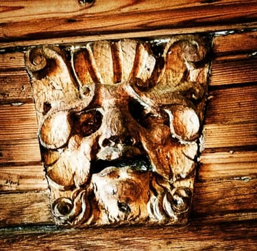 an old carving of a Green Man face in wood