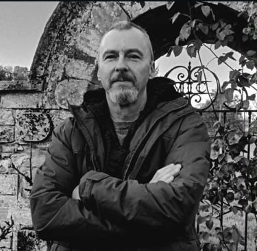 The author Jon Clynch standing by a stone arch with wrought iron gate