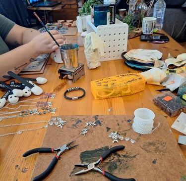 Jewelry making workspace with pliers, silver chains, and beads on a wooden table for DIY crafts.