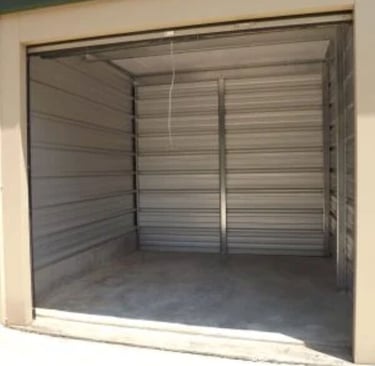 An empty 10X10 foot drive up self-storage unit with metal corrugated walls and a concrete floor.