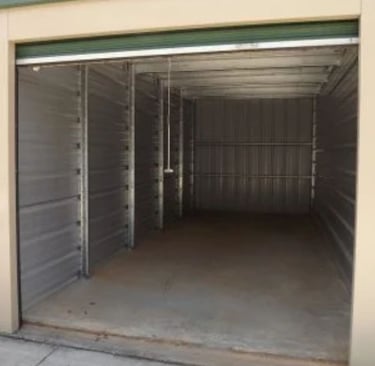 10X25 foot empty metal self-storage unit with an open roll-up door and concrete flooring.