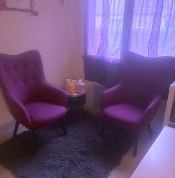 a living room with a purple chair and a black rug