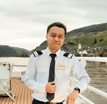 A Head Housekeeper in uniform standing on a deck overlooking a river village.