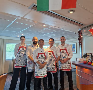 Smiling restaurant staff on a river cruise wearing traditional Hungarian souvenir aprons.