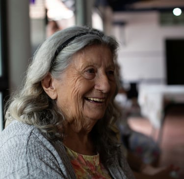 Smiling elderly woman with wavy grey hair laughing during a social gathering