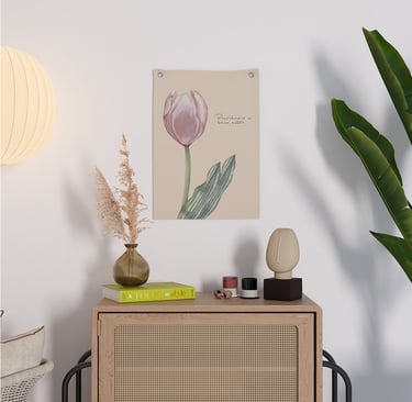 Decoração minimalista para casa com uma gravura de tulipa rosa na parede acima de um armário de vime