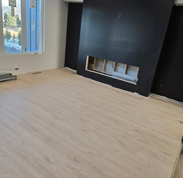 Modern living room featuring light oak laminate flooring and a black accent fireplace wall.