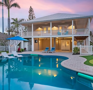 Luxury Florida vacation rental home with a private swimming pool, outdoor patio, and putting green at sunset.