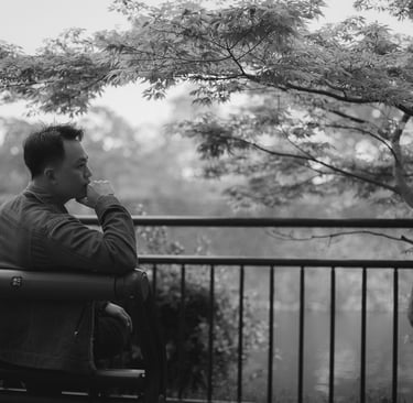Asian man on park bench thinking