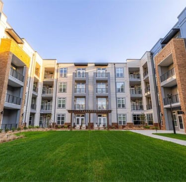 Open green courtyard lawn framed by modern apartment buildings at Leo Loso in Charlotte, North Carolina.