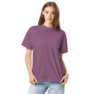 A woman wearing a casual purple cotton t-shirt and light blue jeans against a black background.