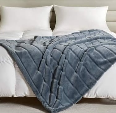 Made bed with plush weighted blanket draped over white bedding for cozy comfort