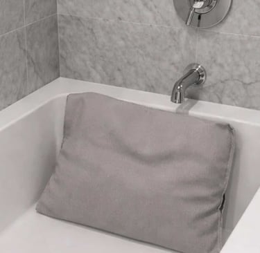 An extra-thick ergonomic bath pillow is displayed inside a white bathtub to show neck support