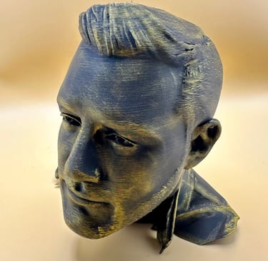 A 3D printed bust of a man with a metallic bronze and black finish on a tan background.