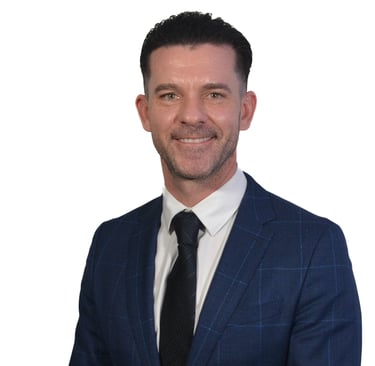 Professional headshot of a smiling businessman in a blue plaid suit and black tie.