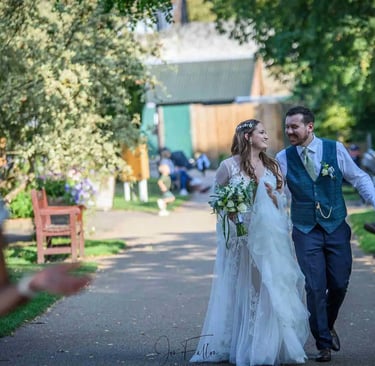 A happy bride and groom walking down a sunny outdoor path at their wedding venue.