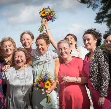 Smiling brides and bridesmaids celebrating a summer wedding with vibrant sunflower bouquets.