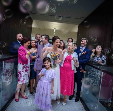 A joyful wedding couple and their guests are showered with bubbles in Lambeth Town Hall