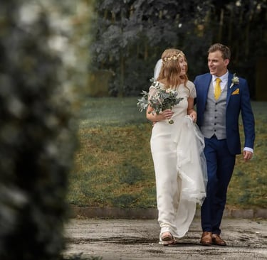 A smiling bride and groom walking together outdoors after their wedding ceremony.