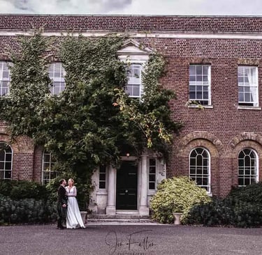 a bride and groom standing in front of a large brick building