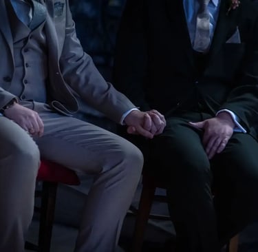 two grooms sitting holding hands